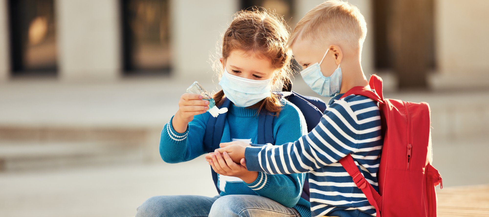 Schoolkids disinfecting hands during coronavirus pandemic.