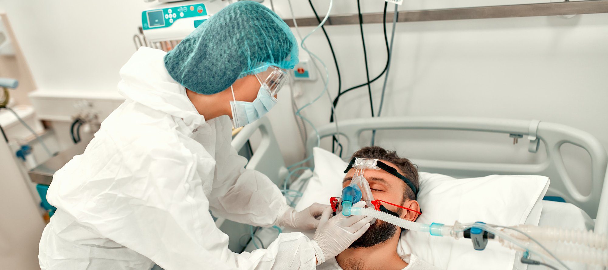 Doctors in protective suits put on a ventilation mask on a sick man with coronavirus disease