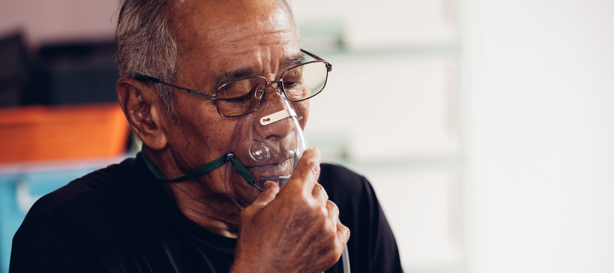 Mature man using respiratory mask to assist breathing