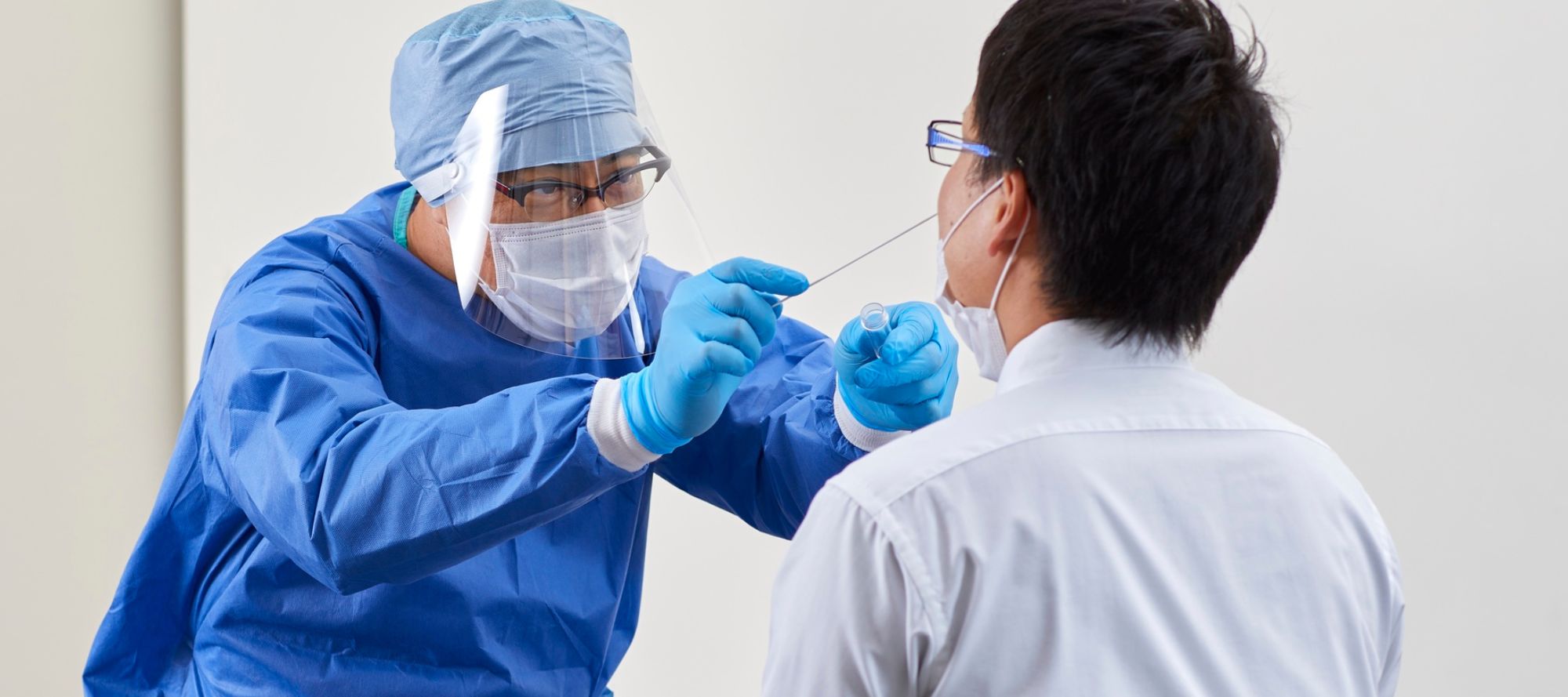 Medical professional in protective wear as he gives swab test to patient
